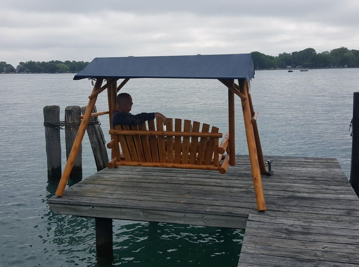 cedar varnished lawn swing with royal blue canopy for lake front properties